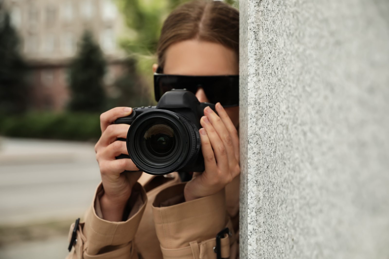 Private detective with camera spying behind wall